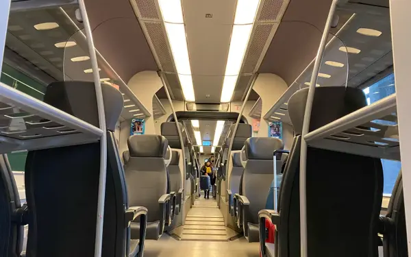 The interior of a train carriage, seats and central aisle